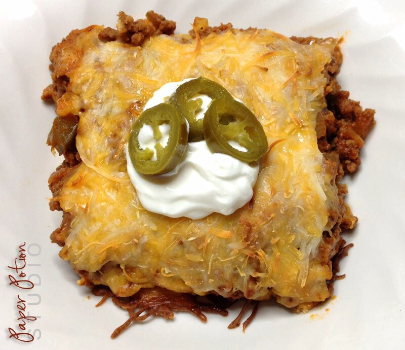 Homepage post card 1: Square of low-carb taco bake with savory crust, melted cheese, sour cream dollop, and jalapeño slices on a white plate